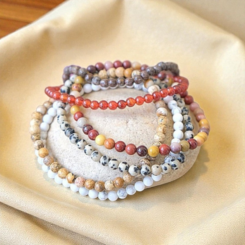 Atelier Tibet stack of 4mm natural stone bracelets in various colours including red, white, beige, brown, and black spots.
